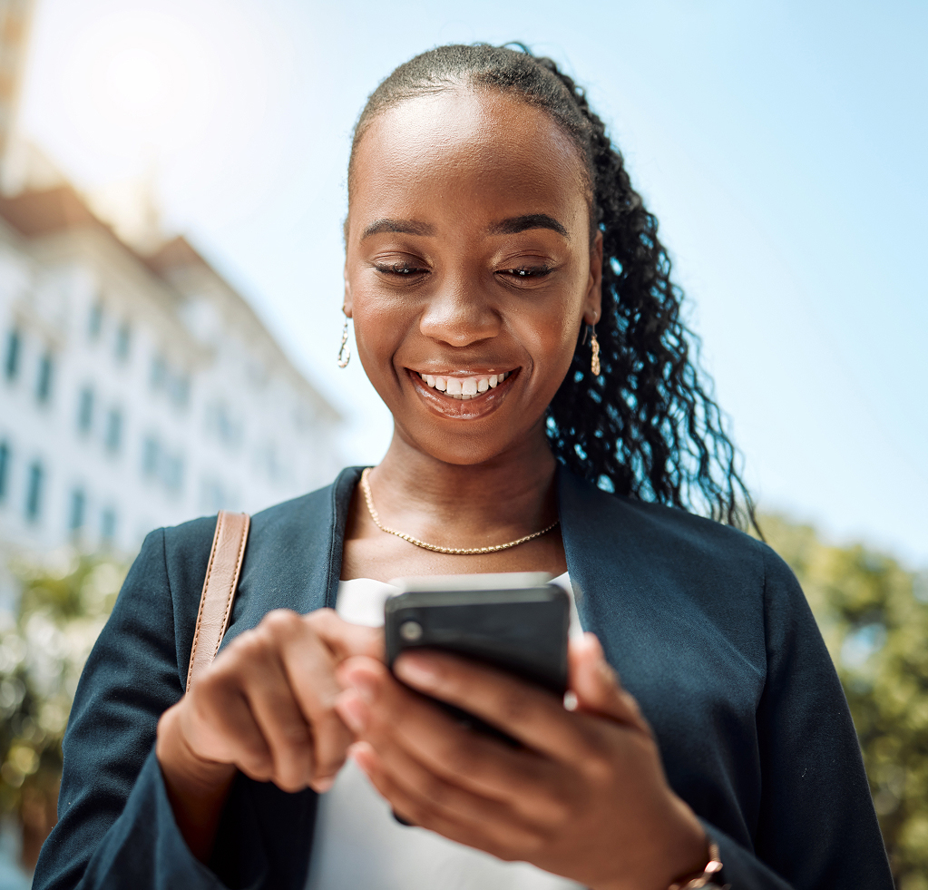 Ragazza sorridente che usa lo smartphone per strada